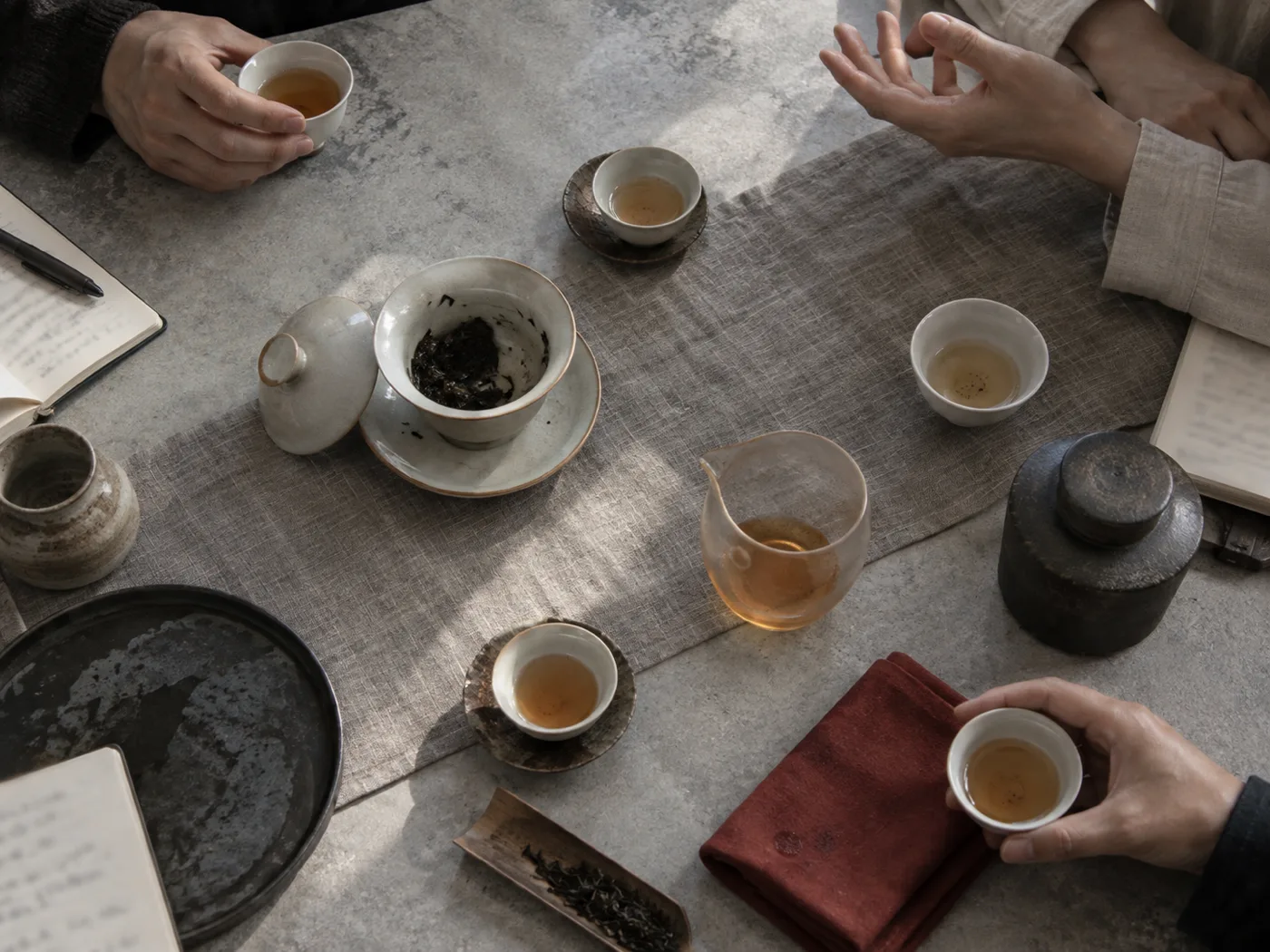 中国茶の茶器とノートを囲み、語り合っているテーブル